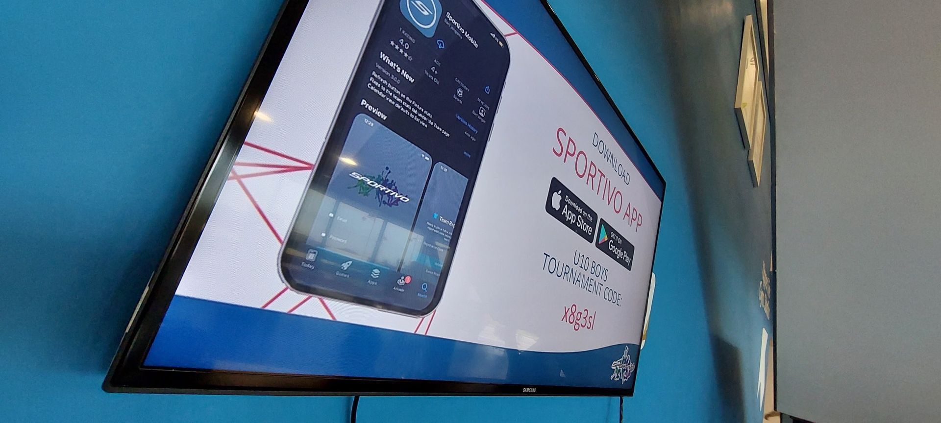 Wall-mounted TV displaying a smartphone ad on a blue wall