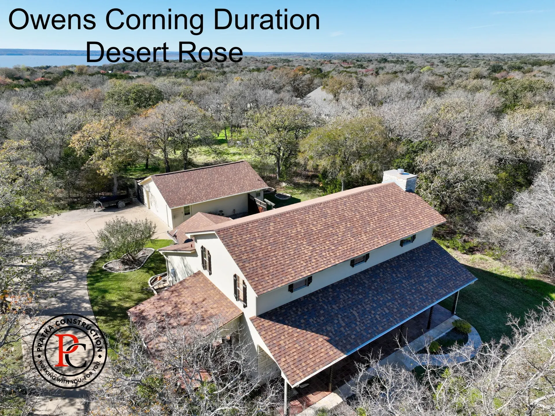 Aerial view of a house with a Desert Rose colored roof, surrounded by trees.