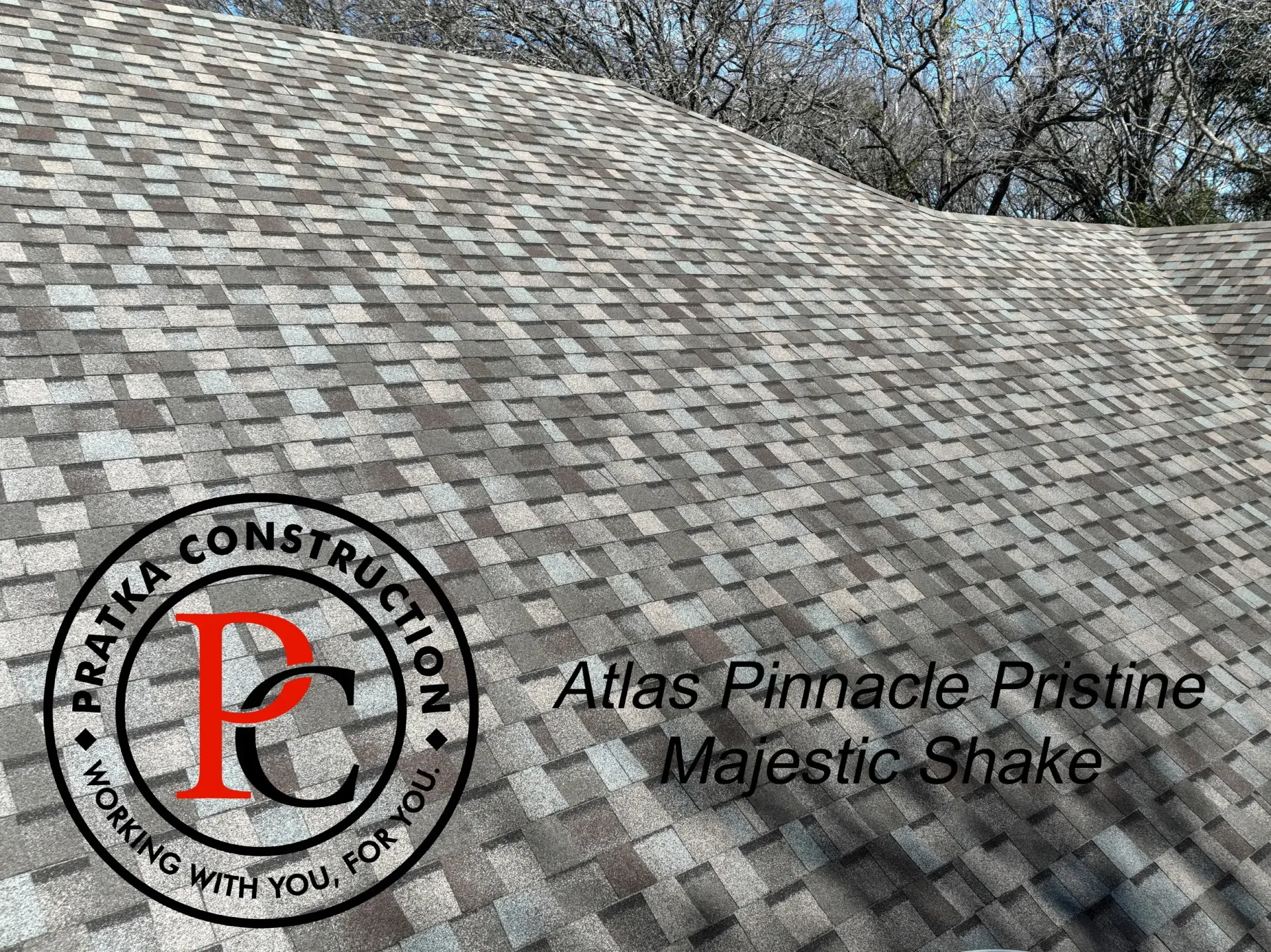 Roof with grey and white shingles; Pratka Construction logo and product name “Atlas Pinnacle Postine Majestic Shake”.