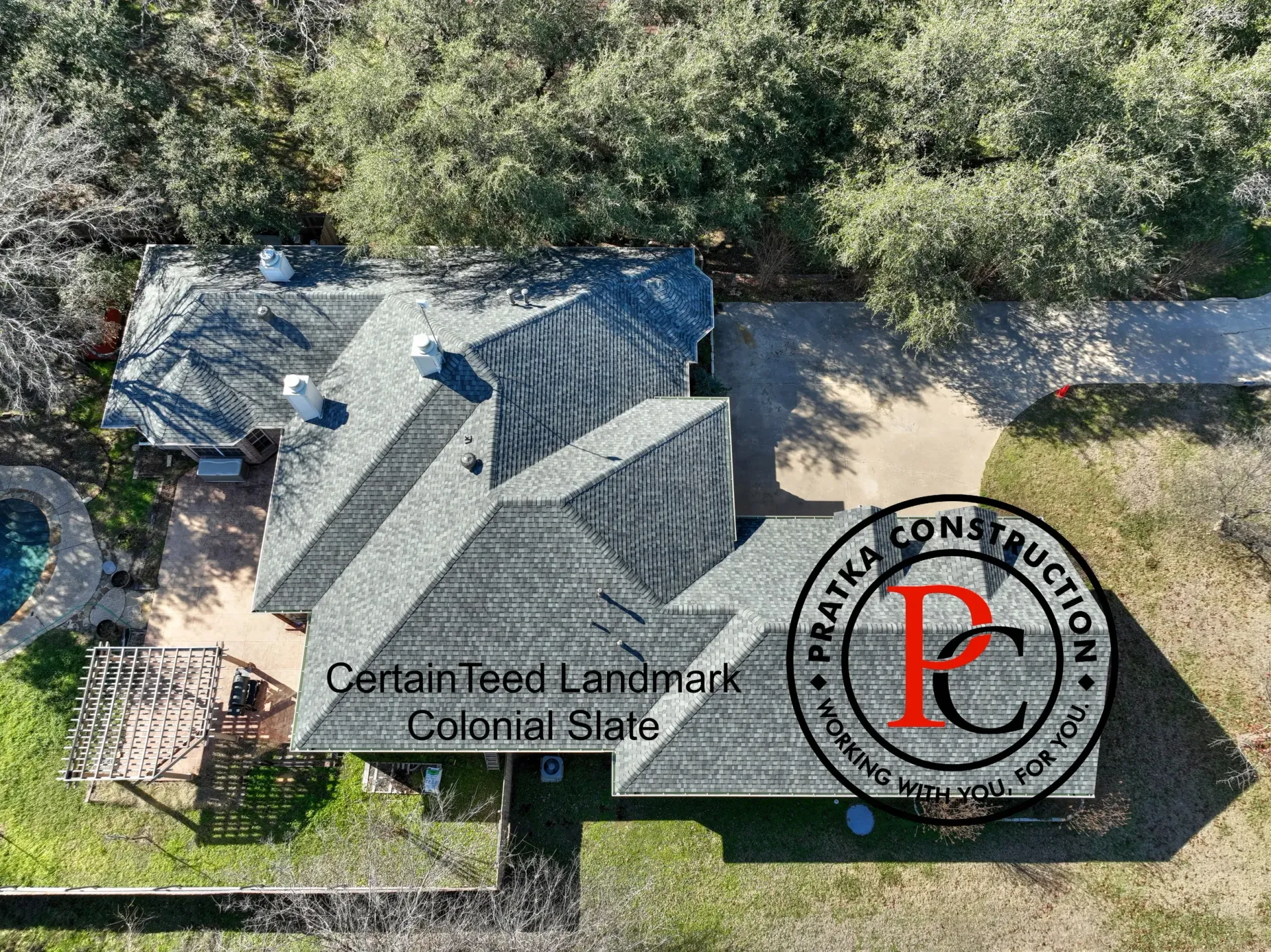 Overhead view of a house with a gray roof, asphalt shingles, and a pool.