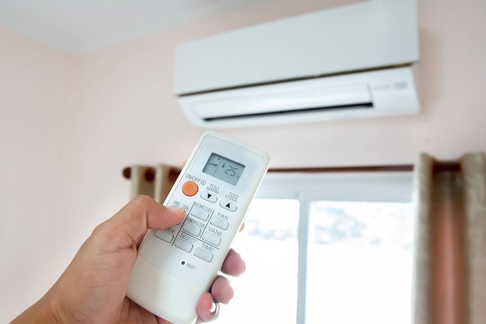 Person Turning On Air Conditioner — Brod’s Refrigeration & Air Conditioning in Gilgandra, NSW