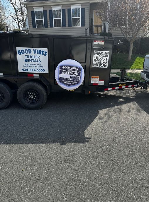 Black trailer with Good Vibes Landscaping signs parked on a residential street.