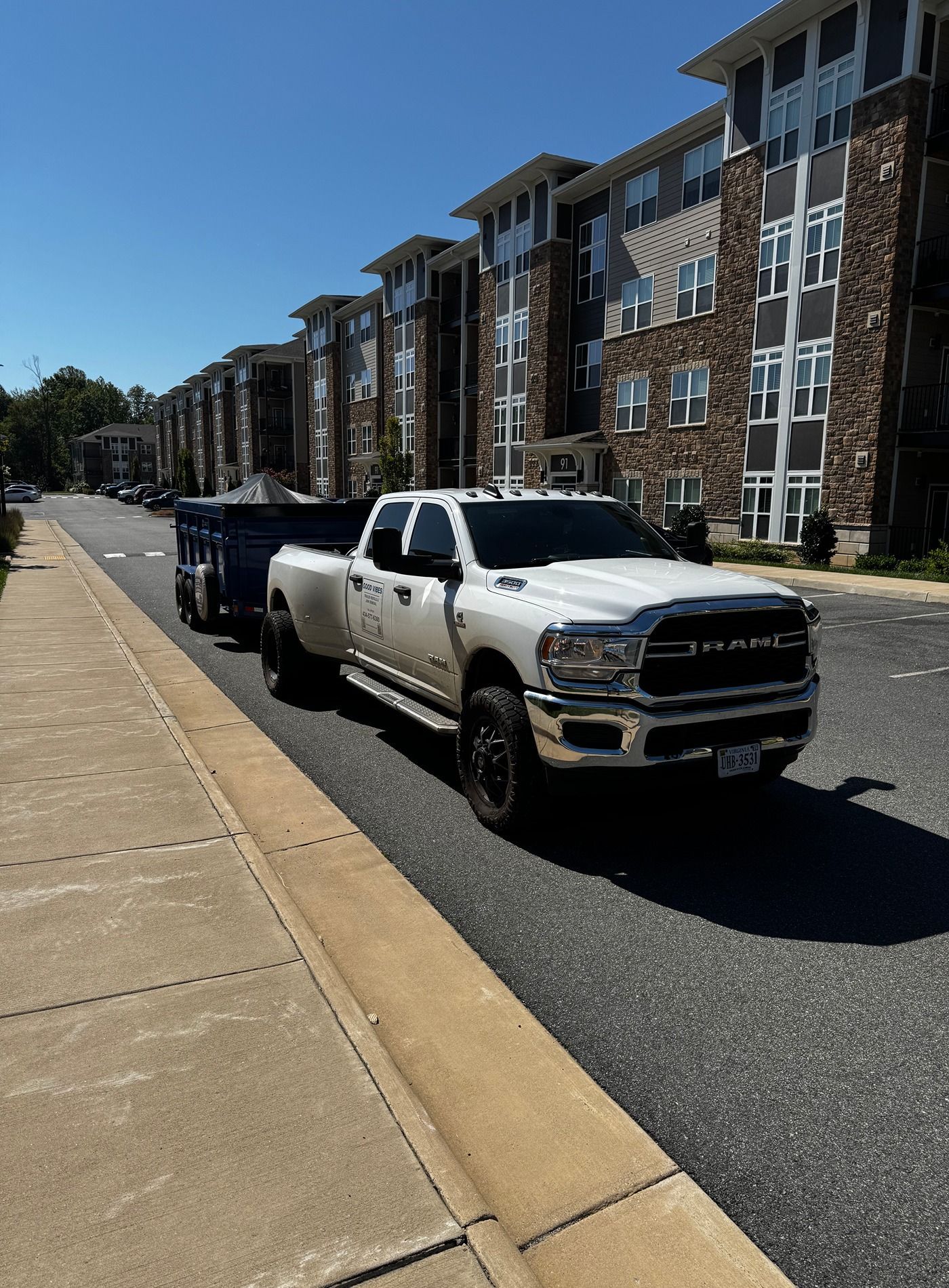 White pickup truck parked along a city street beside apartment buildings on a sunny day