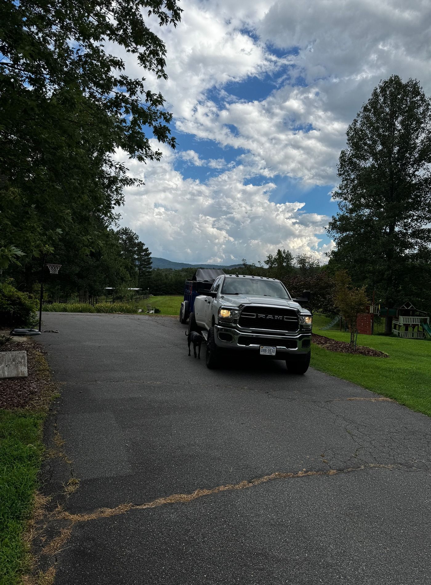 Black truck parked on a paved road under a cloudy sky, with trees and grass along the roadside.