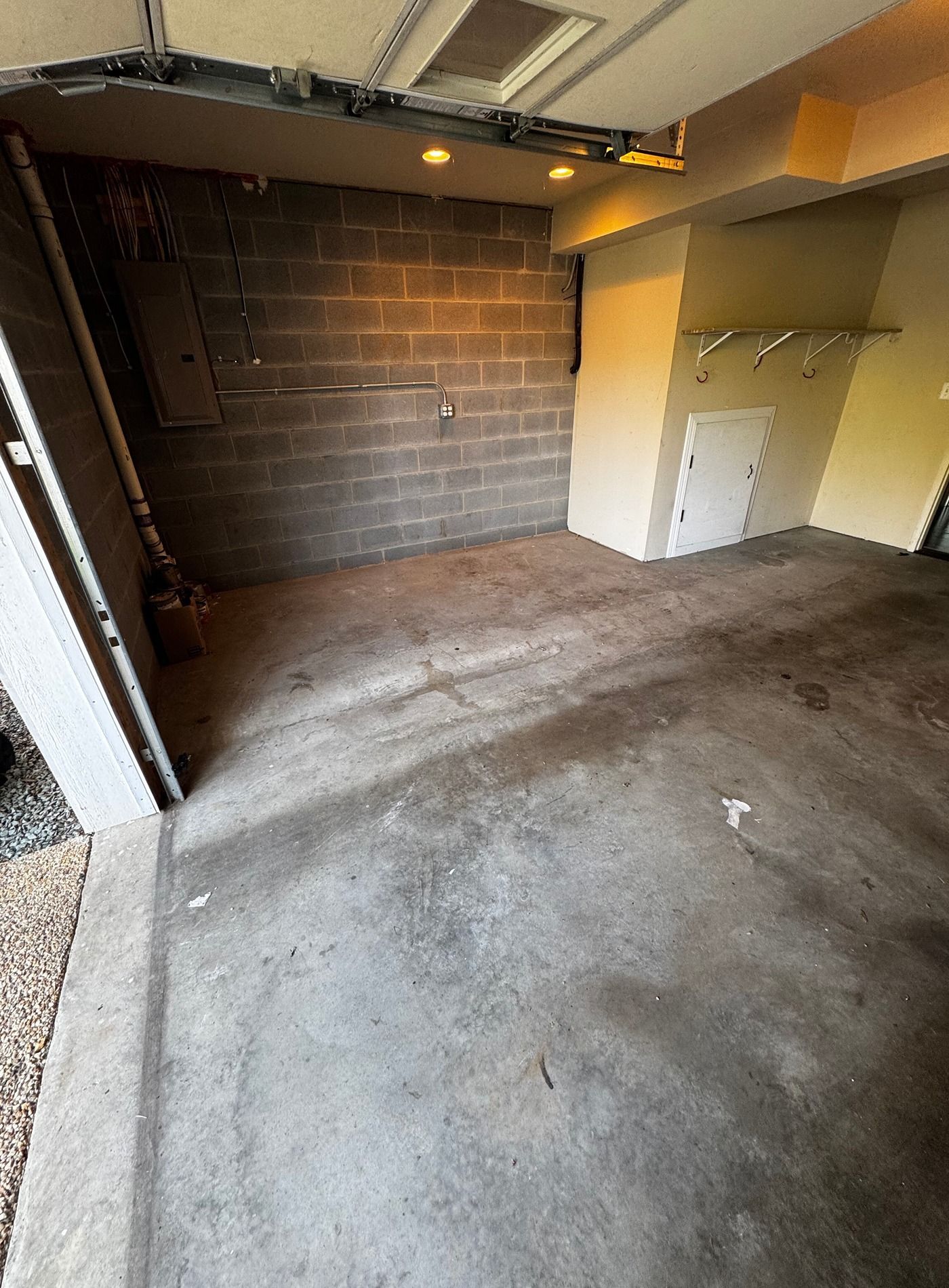 Empty garage with concrete floor, exposed brick wall, and a small utility alcove on the right.