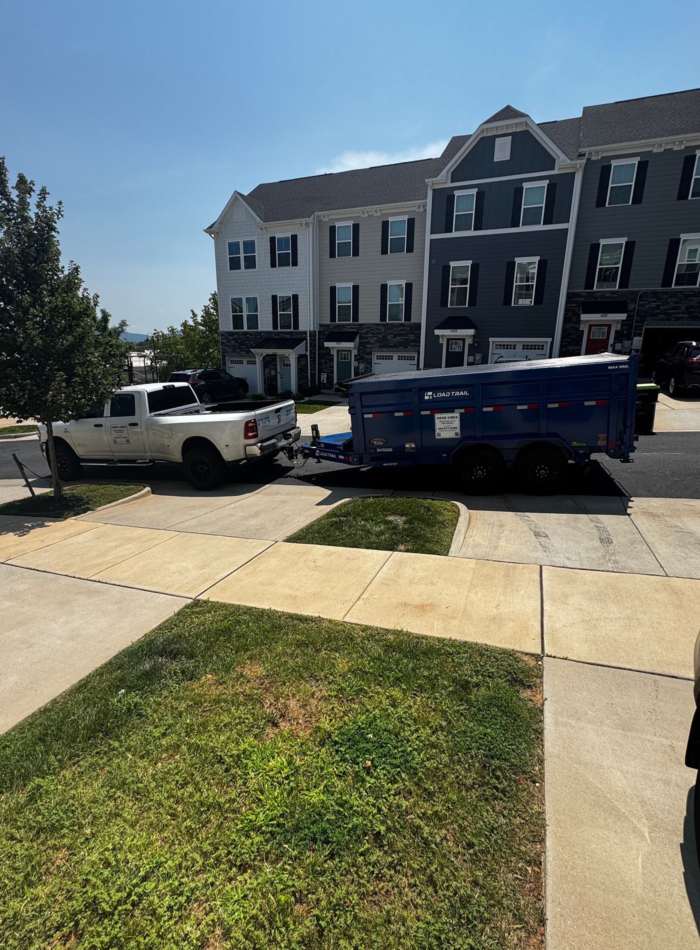 Townhouses with parked white pickup and blue dumpster on a sunny residential street