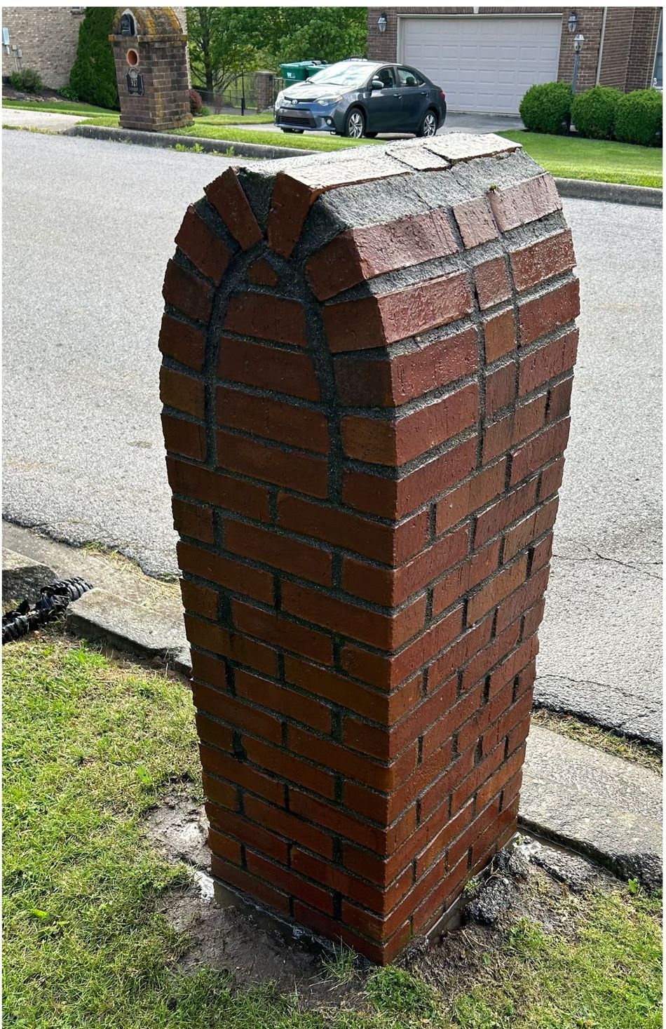 A brick post with a car parked in the background