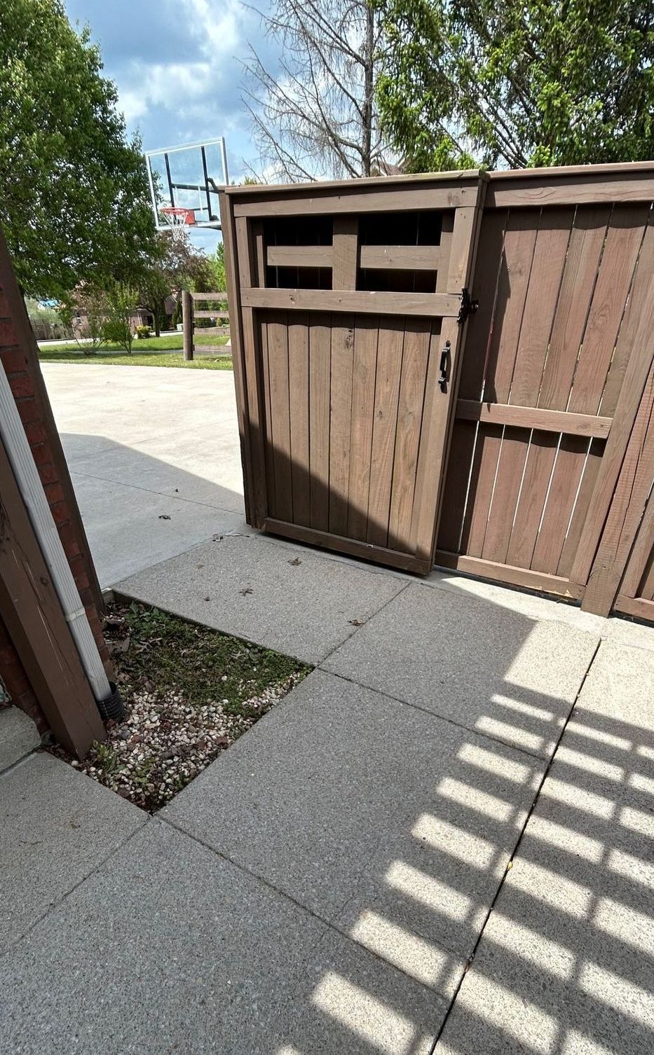 A wooden fence with a trash can in the middle of it.