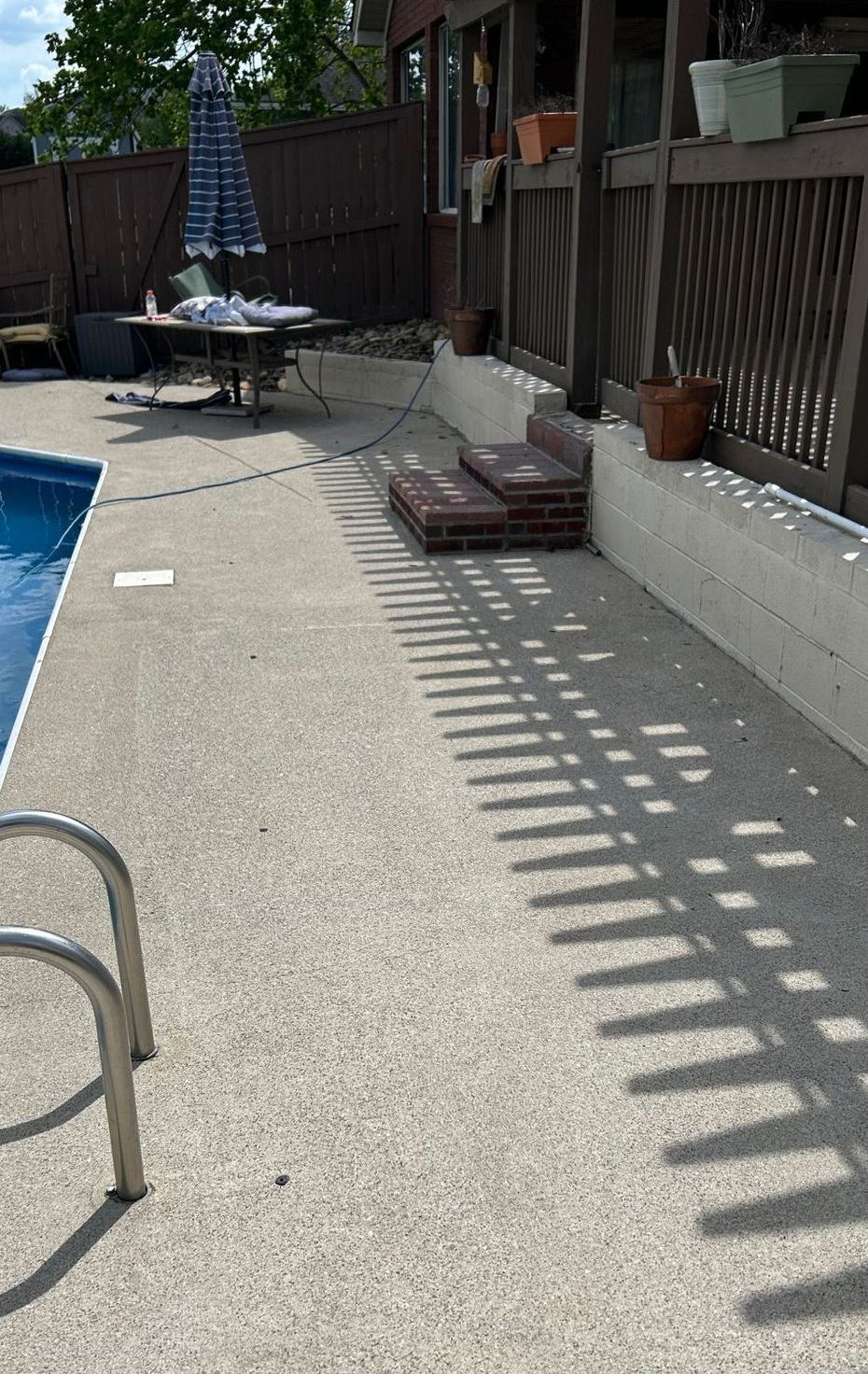 There is a swimming pool in the backyard with a table and chairs.