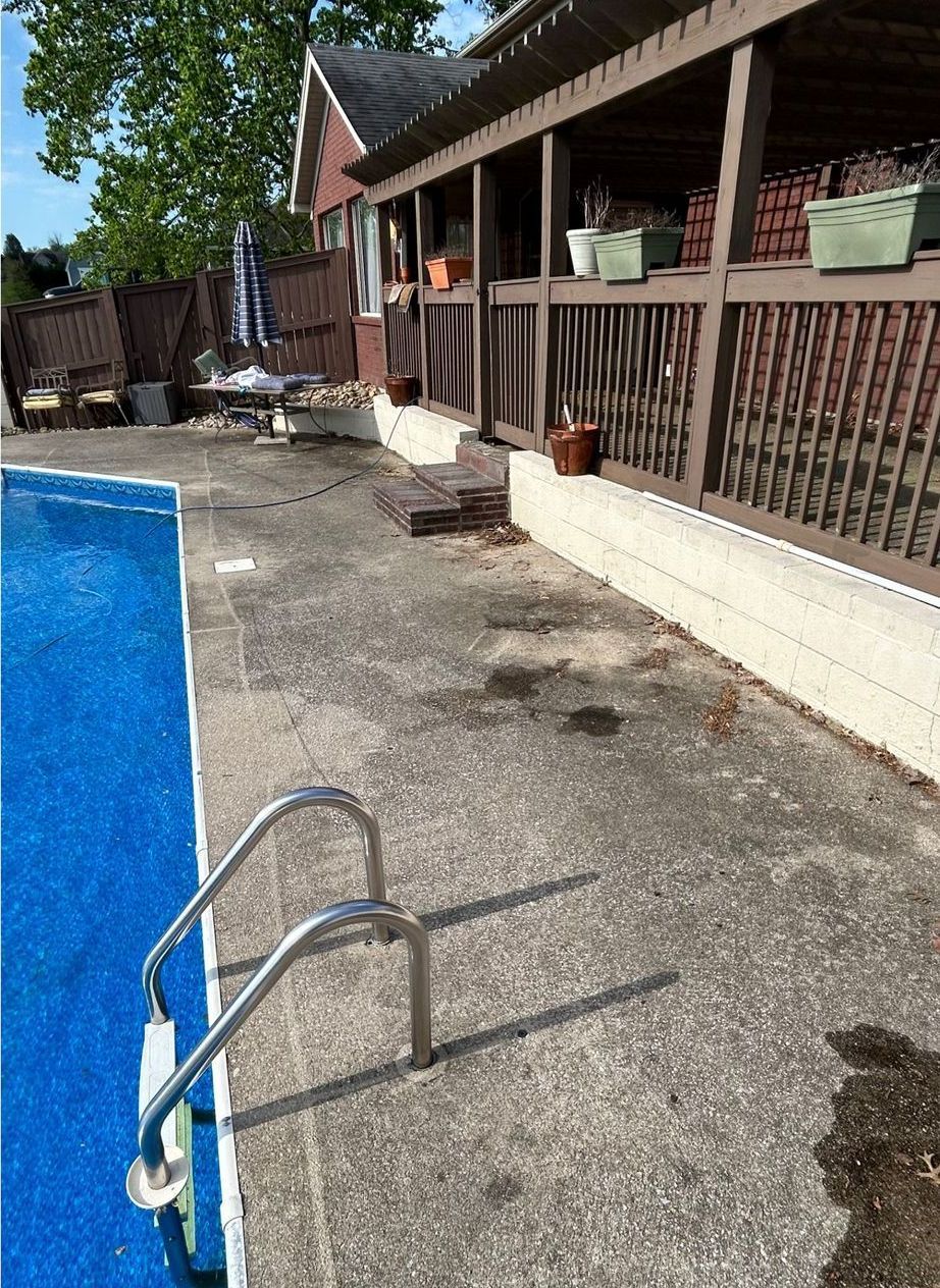 A swimming pool with stairs leading to it and a house in the background.