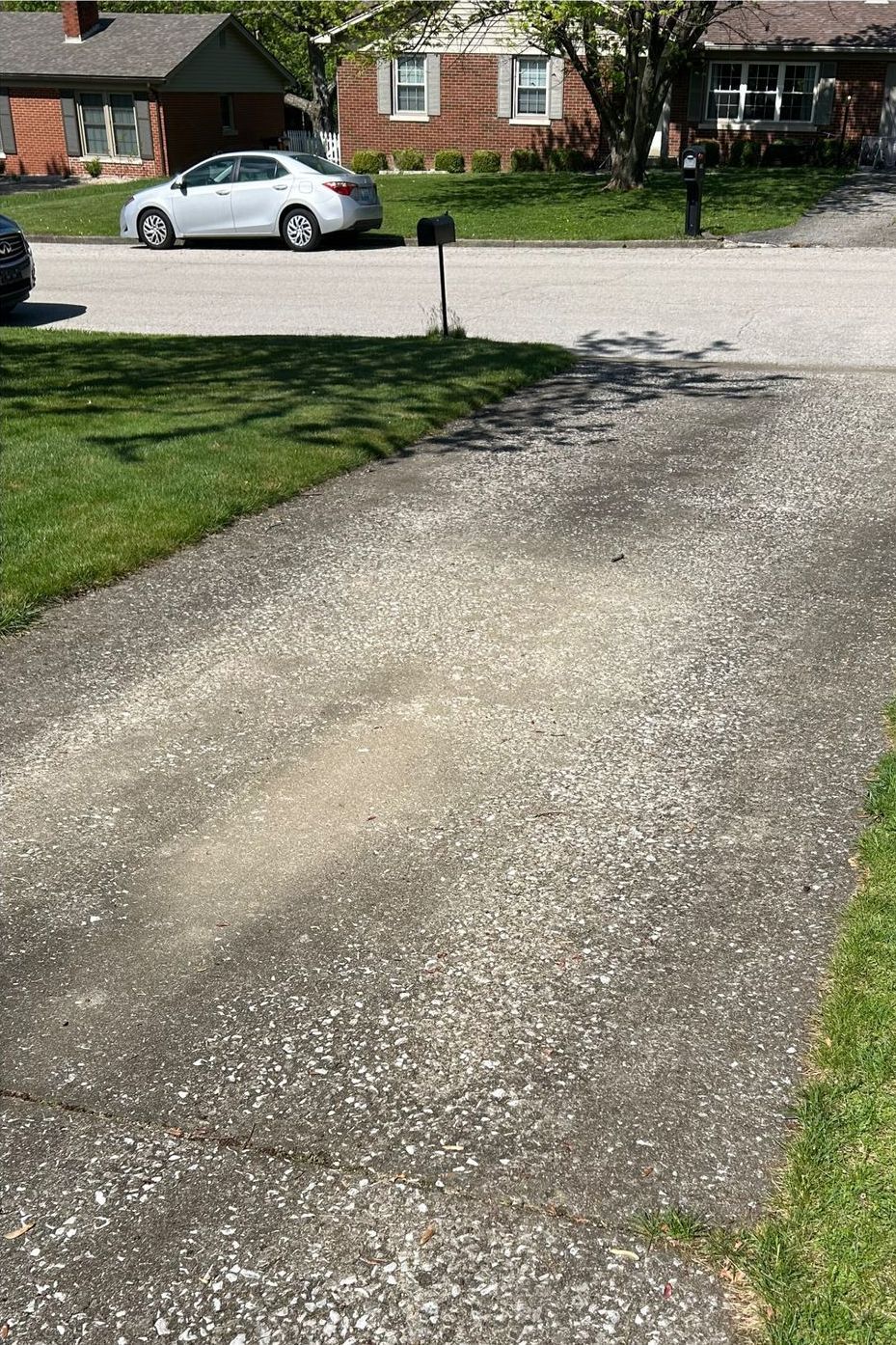 A white car is parked on the side of the road next to a mailbox.