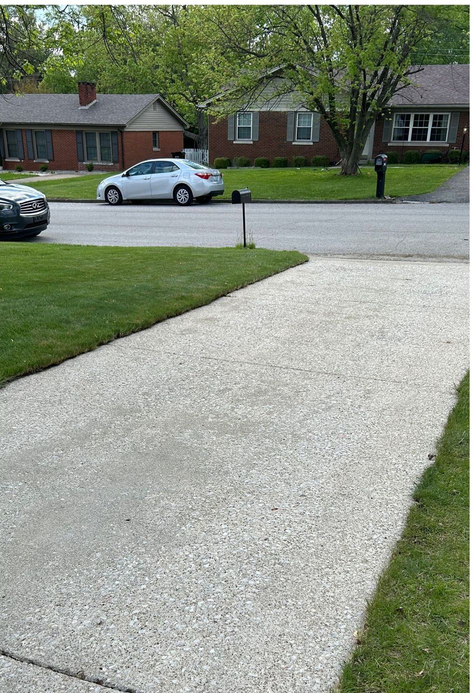 A white car is parked on the side of the road next to a sidewalk.