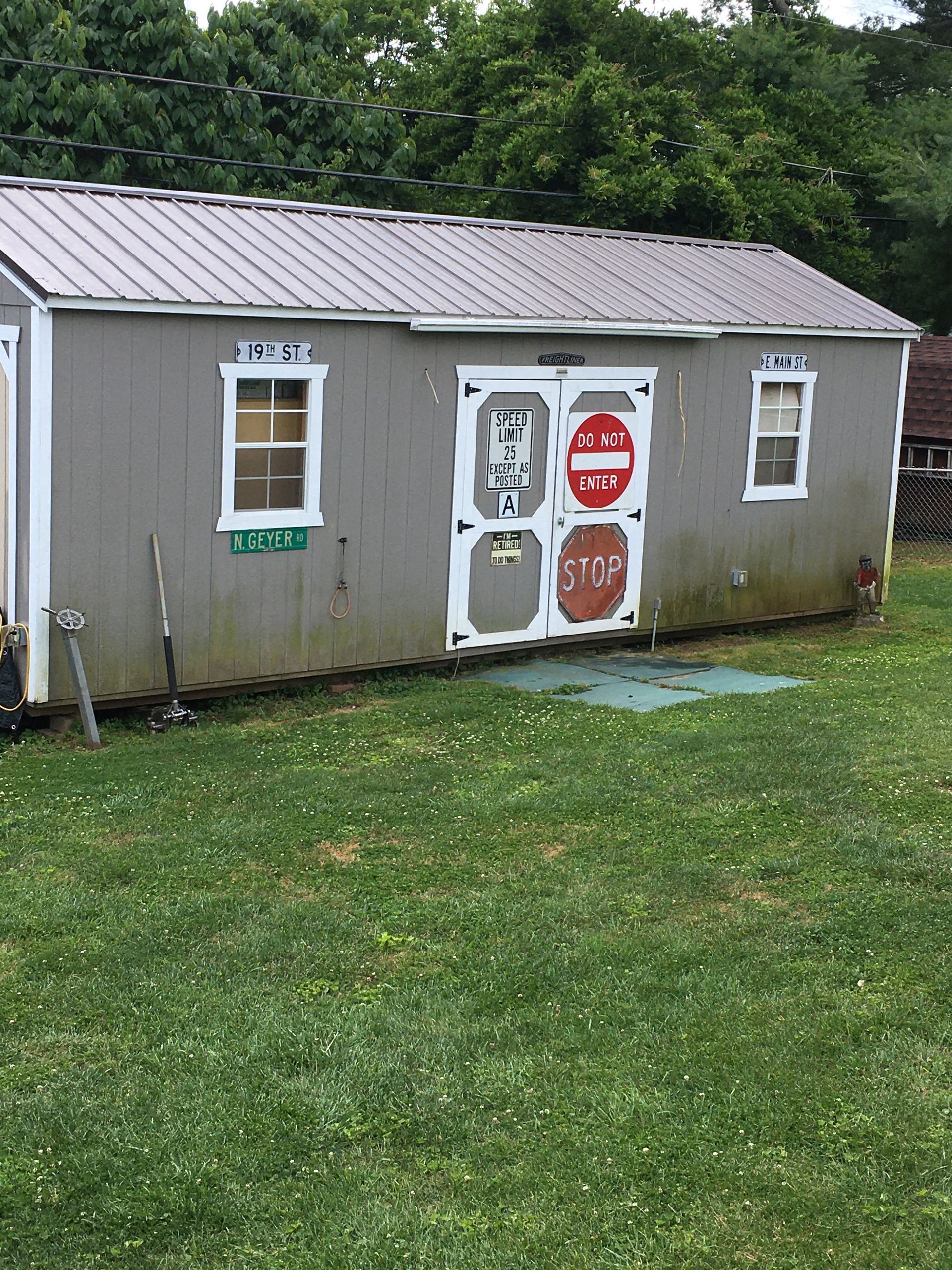 A small shed is sitting in the middle of a grassy field.