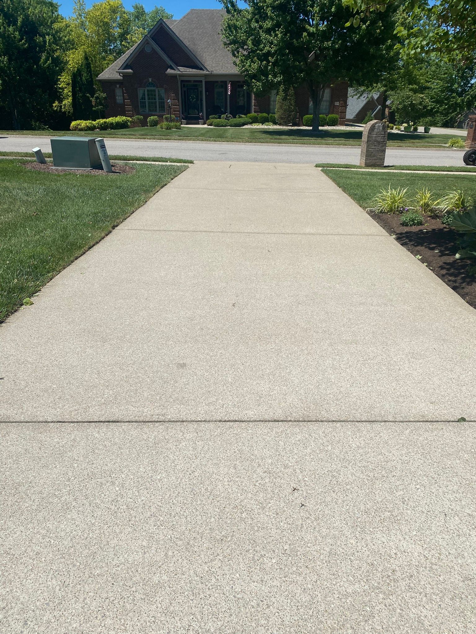 A concrete walkway leading to a house in a residential neighborhood.
