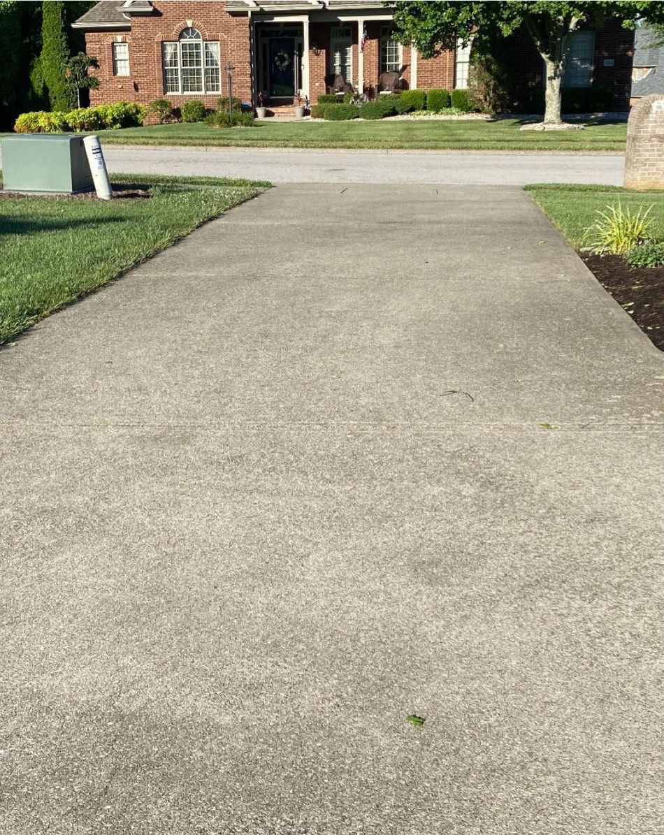 A concrete driveway leading to a brick house.