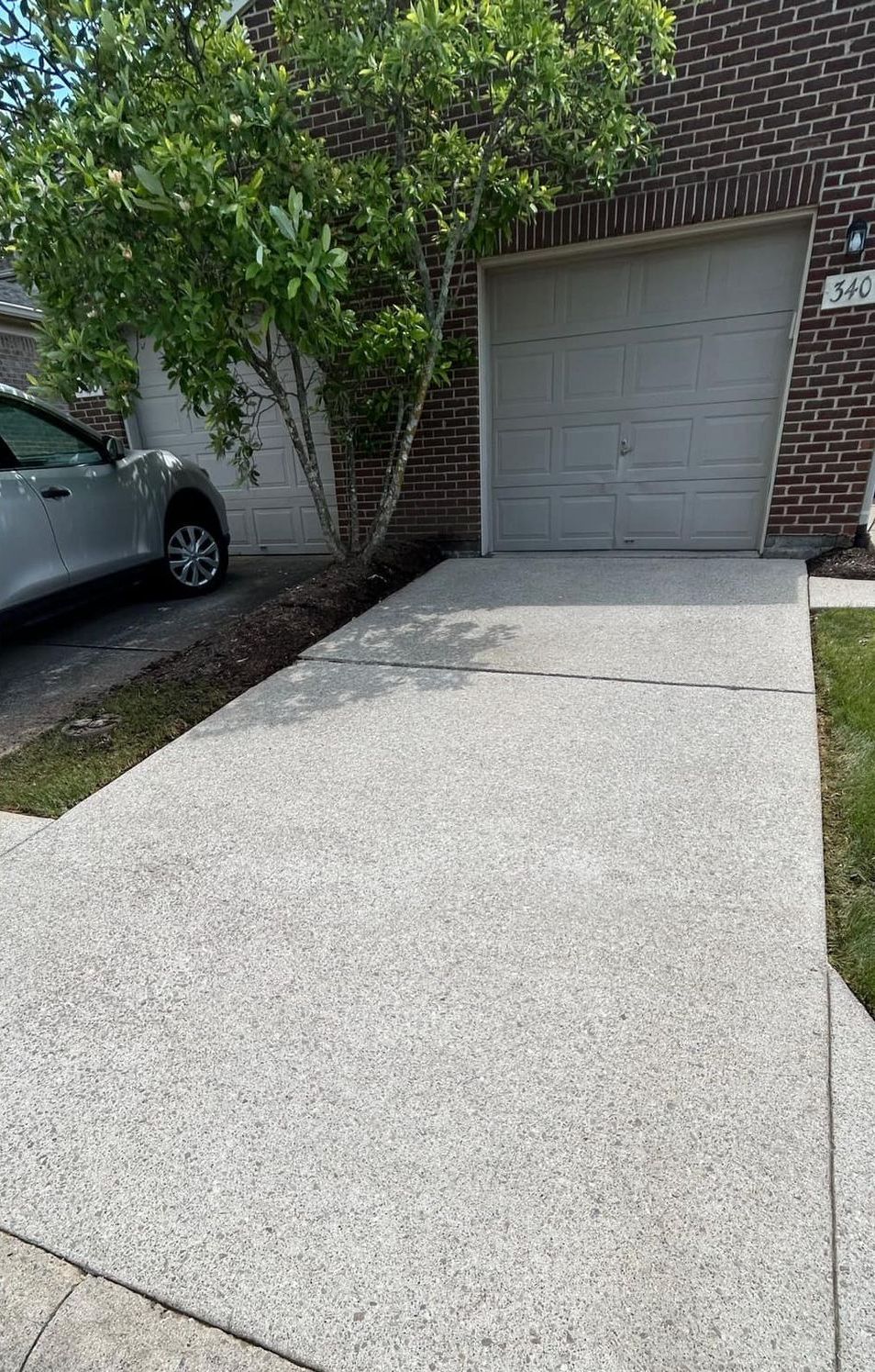 A car is parked in a driveway next to a garage.