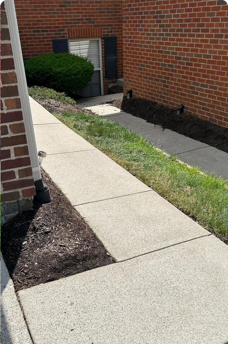 There is a sidewalk leading to a brick building.