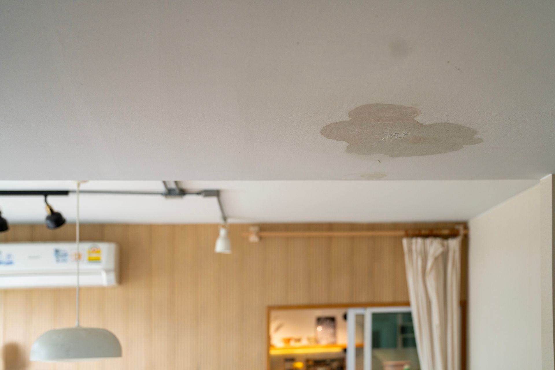 Water stain on a white ceiling in a room, indicating a leak.