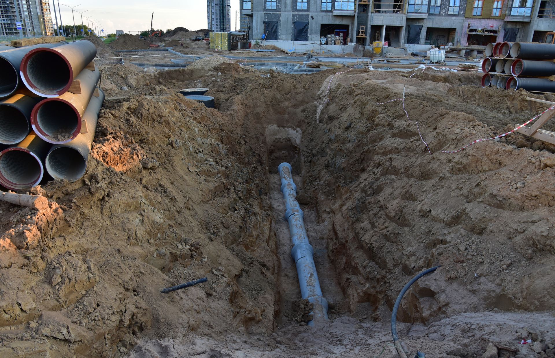 Construction site with trench and pipes.