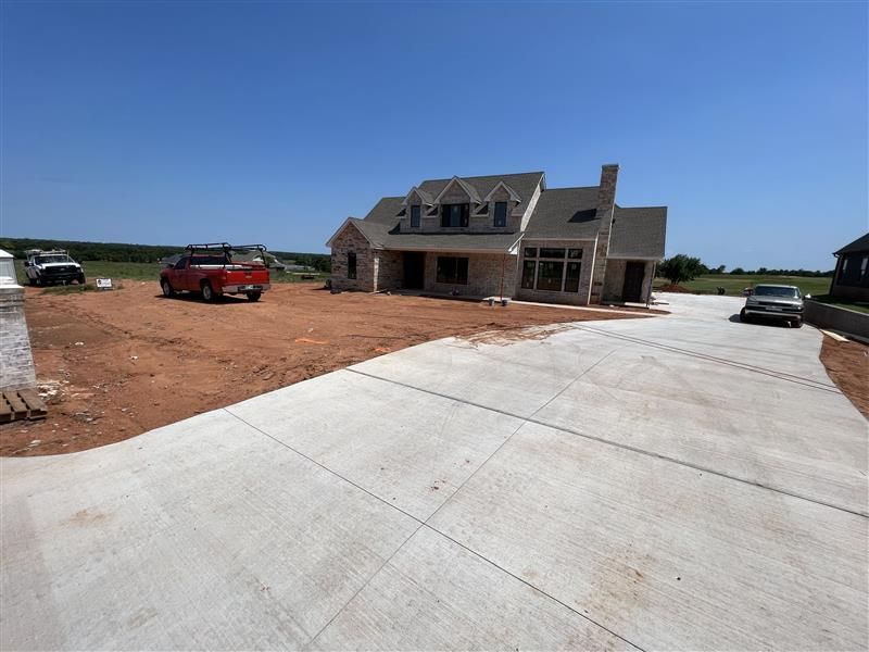 New house under construction, with concrete driveway and red truck.