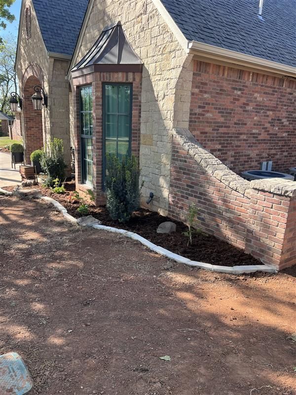 Exterior view of a house with brick and stone, small garden bed, and decorative edging.