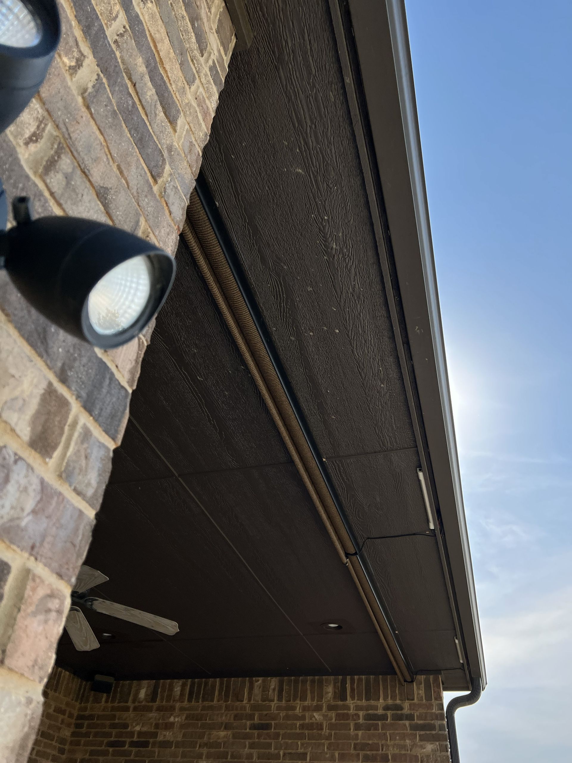 View of a brick building with a dark textured ceiling, lights, and a glimpse of the sky.