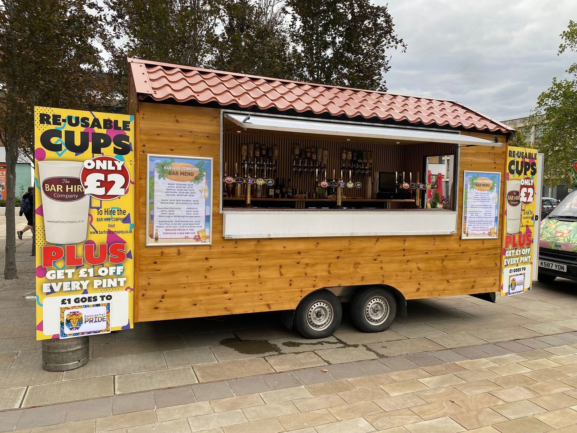 Food and beverage kiosk on wheels with beer taps, selling drinks in reusable cups.