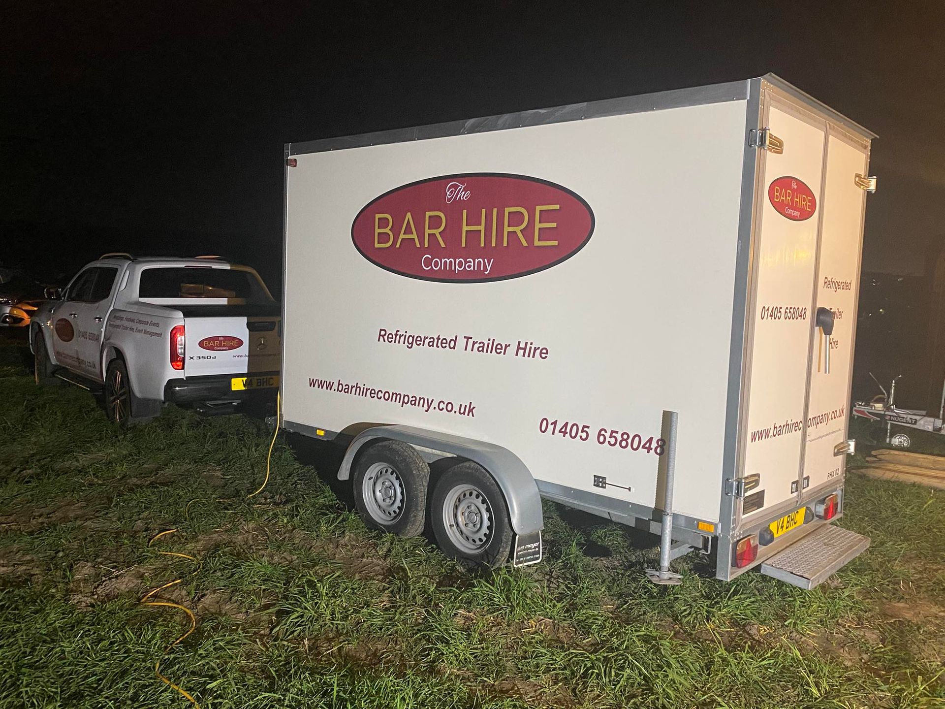 White truck towing a bar hire trailer at night; trailer has Bar Hire logo and contact info.