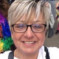 Woman with short blonde hair and glasses smiles.