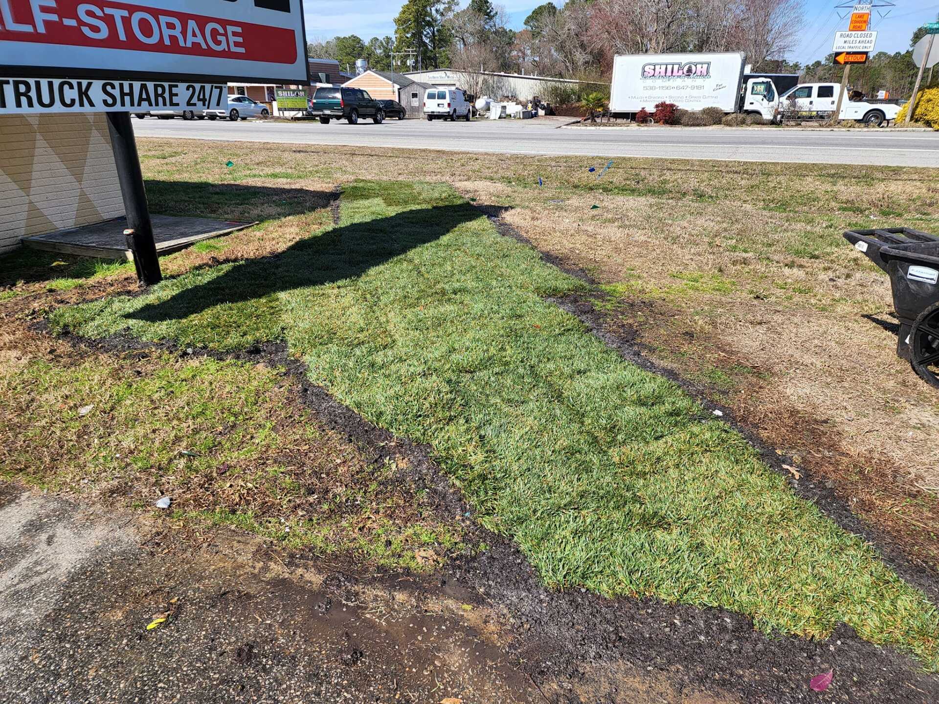 Fresh sod laid in a roadside patch, next to a building with a self-storage sign.