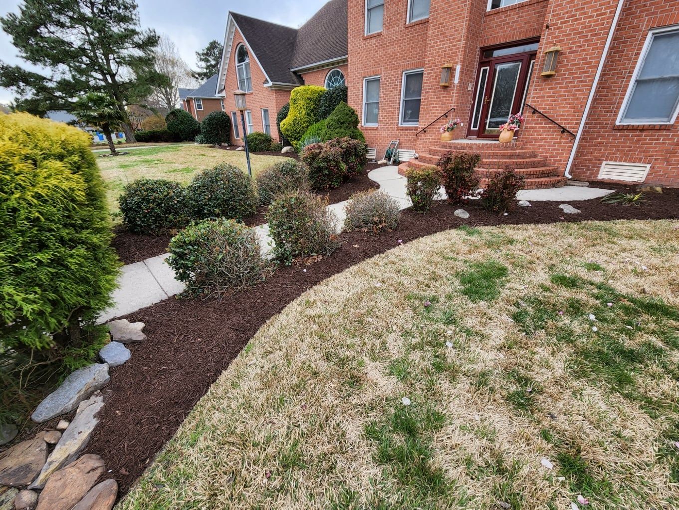 Brick house with landscaped front yard, mulch beds, walkway.