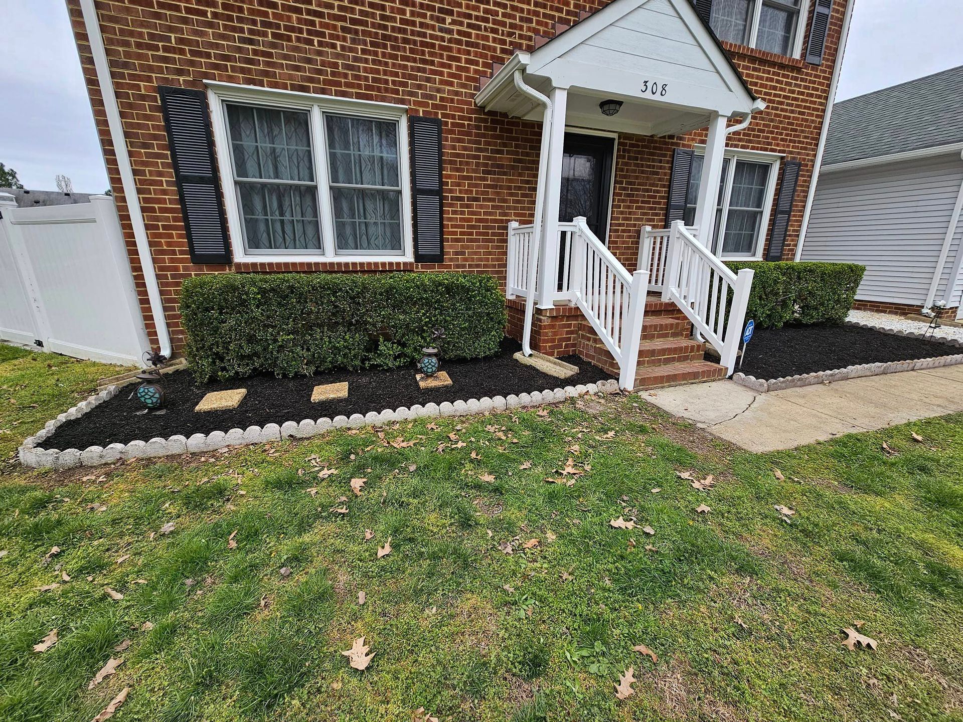 Brick house with white trim, black shutters, and well-kept landscaping.