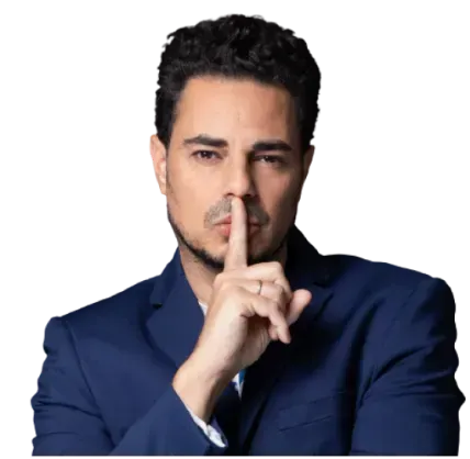 גבר בחליפה כחולה כהה, מצמיד אצבע לשפתיו במחוות השתקה, על רקע לבן