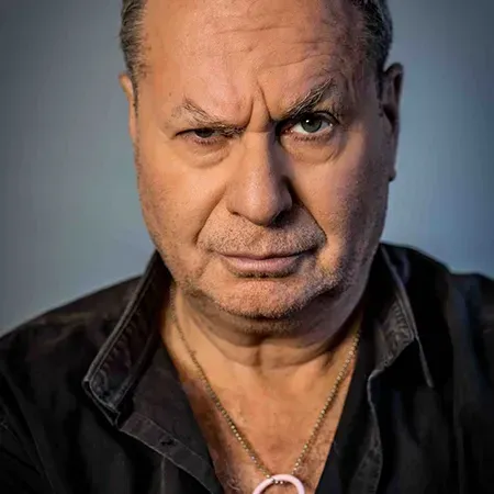 דיוקן תקריב של גבר רציני בחולצה שחורה, המביט ישירות למצלמה.