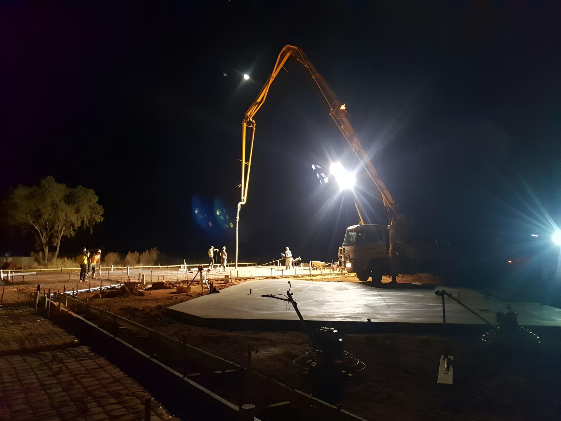 A Construction Site At Night With A Crane Pumping Concrete — Heartland Concrete In Gillen, NT