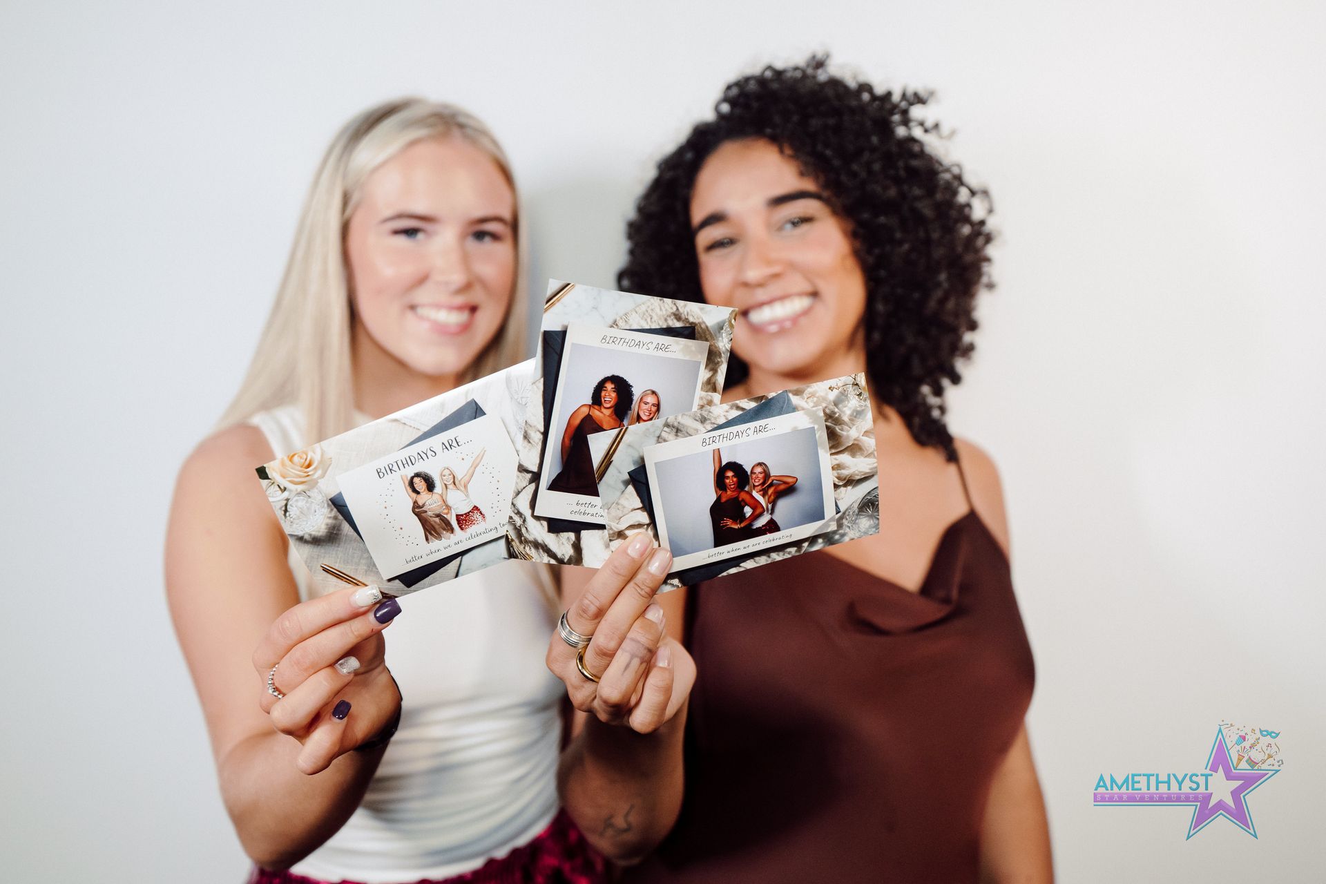 Two adult guests hold several printed Birthday Experience photo keepsakes.