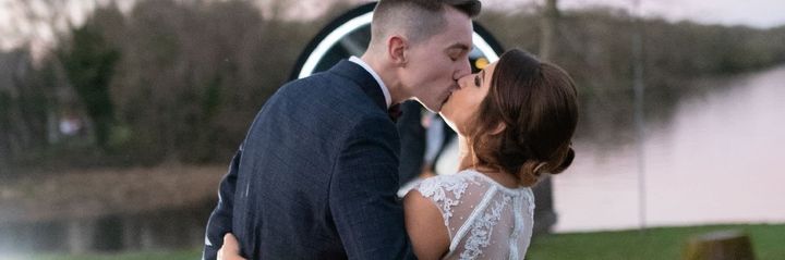 Couple kissing outdoors beside a softly lit fountain at dusk
