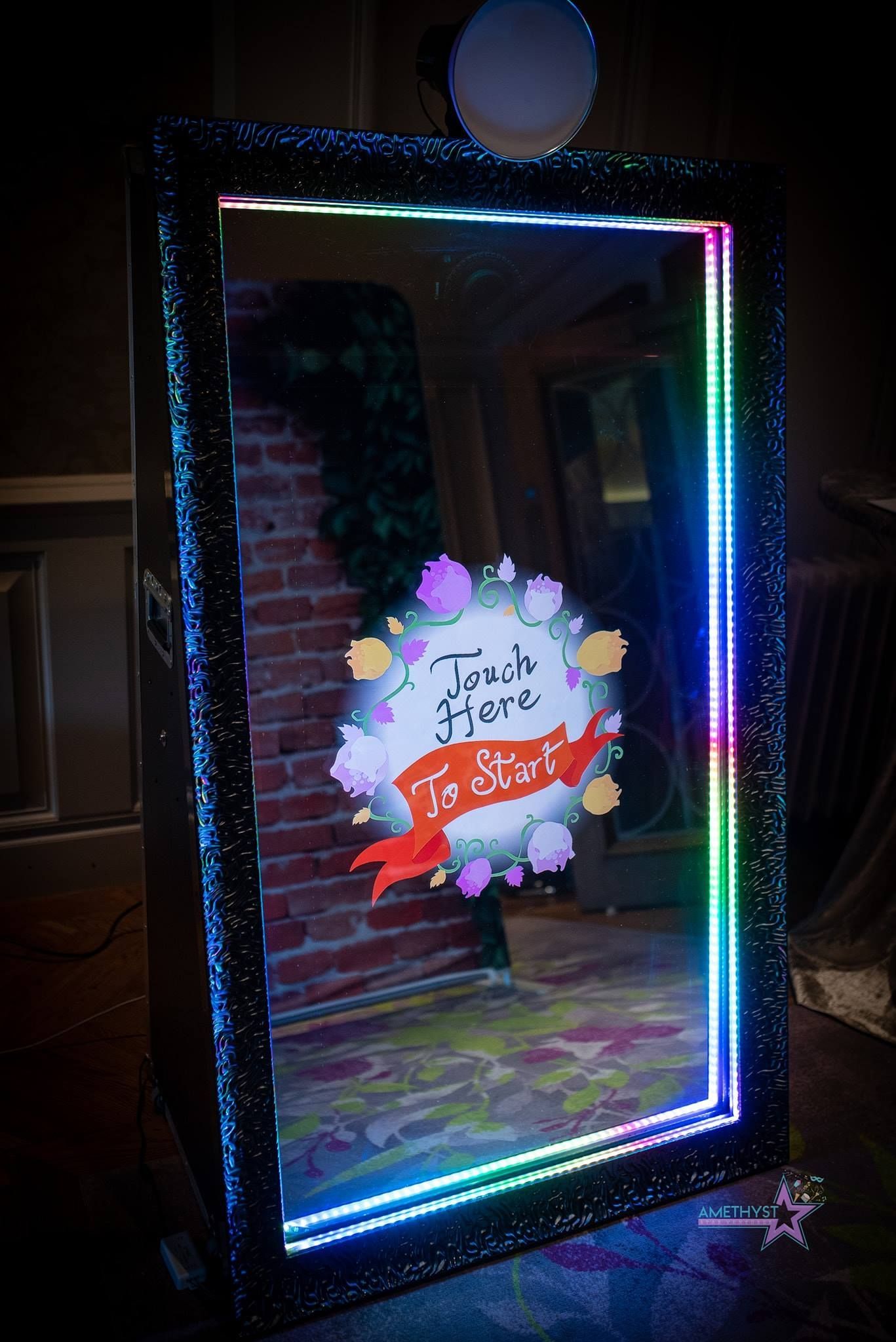 Rectangular LED light frame with a colorful floral graphic glowing in a dark room