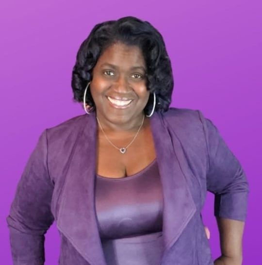 Smiling woman in a purple blazer and top against a purple background