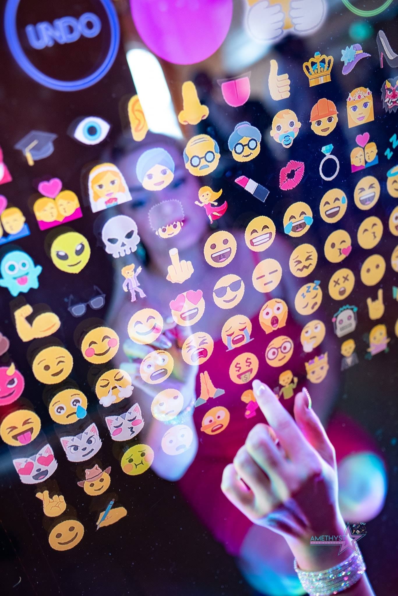 Hand using a digital emoji selection screen with colorful emoji icons and an “UNDO” button