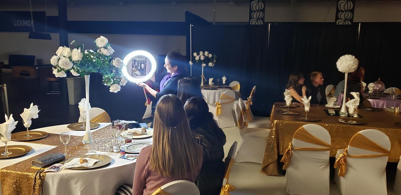 Banquet hall with gold table settings, white floral centerpieces, and guests seated at round tables under dim lighting
