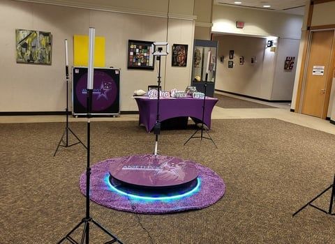 Purple-themed event setup with a glowing circular platform and display table in a lobby area
