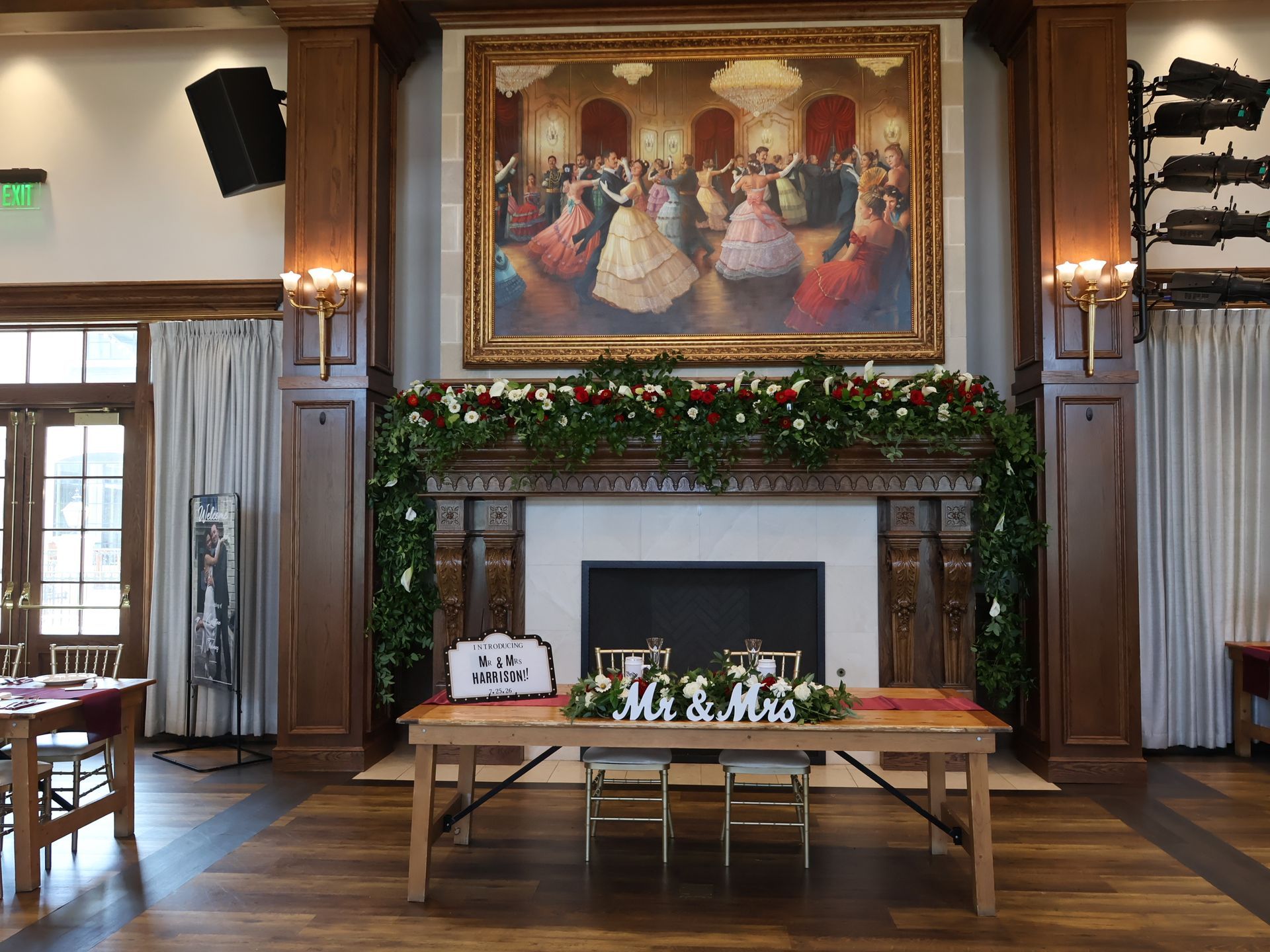 Decorated fireplace and sweetheart table with burgundy and white flowers at the Harrison wedding reception