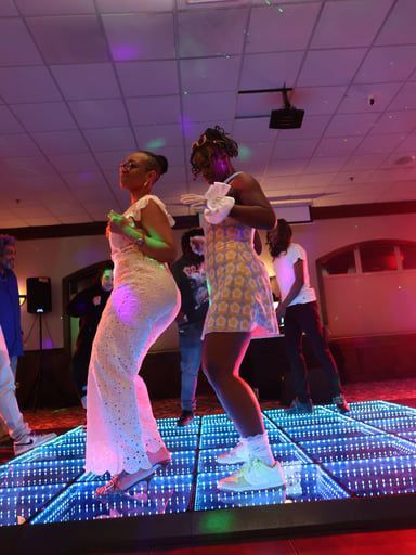 Two people dancing on a glowing LED floor in a dim indoor venue
