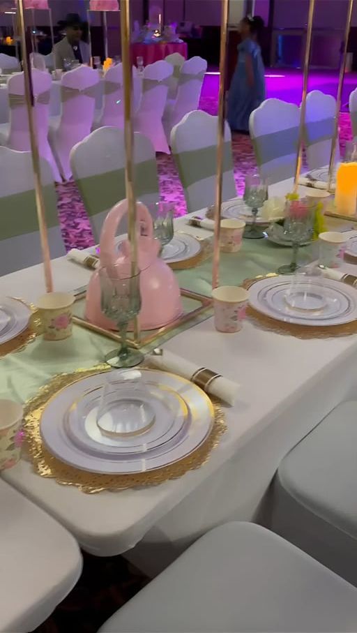 Elegant banquet table with gold-rimmed plates, pink swan centerpiece, and mirrored decor under purple lighting
