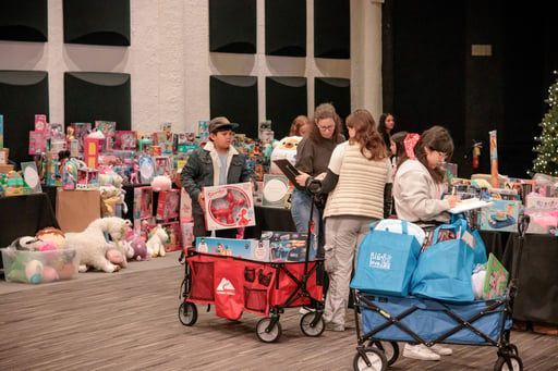People browsing colorful pet merchandise at a pet event, with shopping carts and bags in the foreground