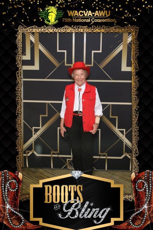 Person in red hat and vest stands on a “Roots & Bling” event backdrop with ornate gold-and-black design