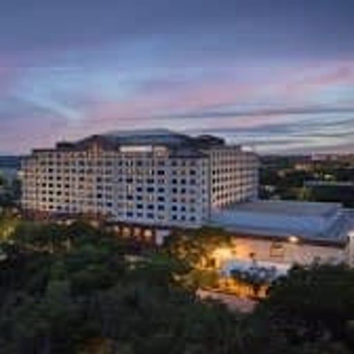 Large hotel building at dusk with lit windows under a pink-blue sky
