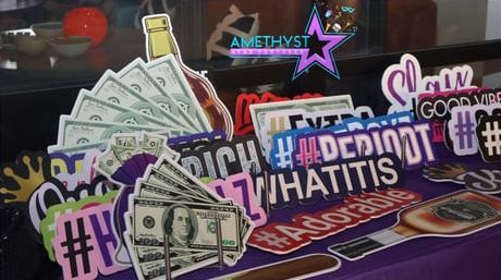 Decorated event table with cash props, neon signs, and hashtag signs on a red-and-blue tablecloth