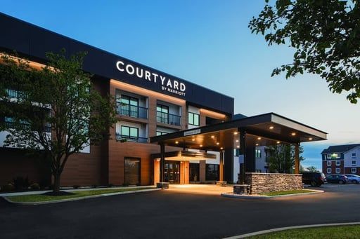 Courtyard hotel exterior at dusk with illuminated entrance and stone facade